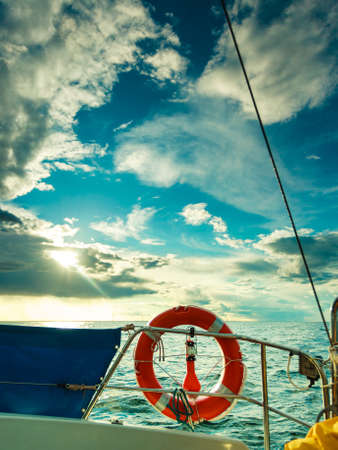 Rescue ring on sailing boat during cruise on water druing sunset through clouds.の写真素材