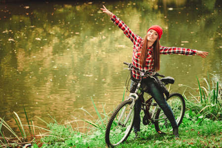 Fall active lifestyle concept. Beauty young woman sporty casual girl relaxing in autumnal park with bicycle, outdoorの写真素材