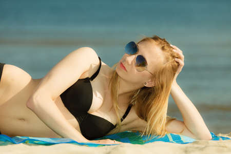 Summertime pleasures, enjoying vacation concept. Woman in bikini sunbathing and relaxing on beachの写真素材