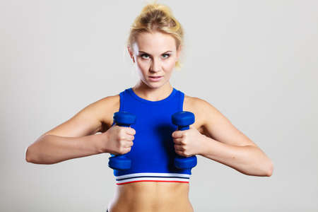 Sporty woman lifting light dumbbells weights. Fit girl exercising building muscles. Fitness and bodybuilding.の写真素材
