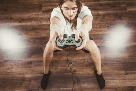 Addiction. Stressed depressed young man playing gaming on pad. Angry guy with controller pad play console. Face expression.の写真素材