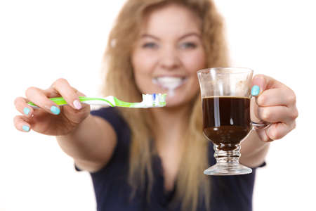 Happy woman holding toothbrush and coffee going to brush her teeth after hot drink. Discoloration...
