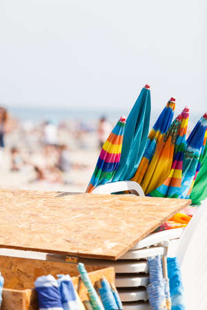Sunbathing equipment concept. Closed sun protective umbrellas on sandy beach during summertimeの写真素材