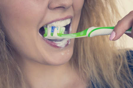 Woman brushing cleaning teeth. Positive girl with toothbrush. Oral hygiene. Toned imageの写真素材