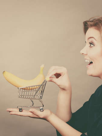 Buying healthy food, vegetarian, gluten free, vegan products. Woman holding shopping cart with banana insideの写真素材