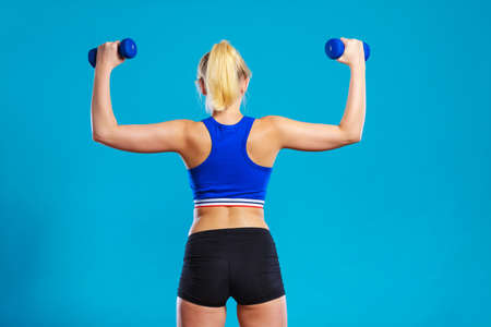 Sporty woman lifting light dumbbells weights. Fit girl exercising building muscles. Fitness and...