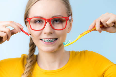 Dentist and orthodontist concept. Young woman smiling cleaning and brushing teeth with braces using toothbrushの写真素材