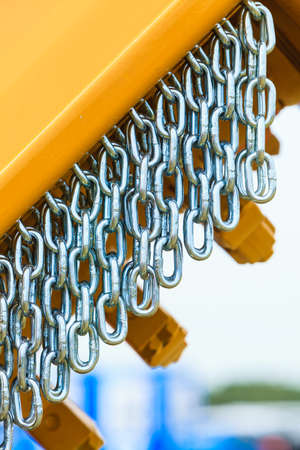 Abstract metal concept. Detailed closeup, lot of silver chains on yellow agriculture machinery