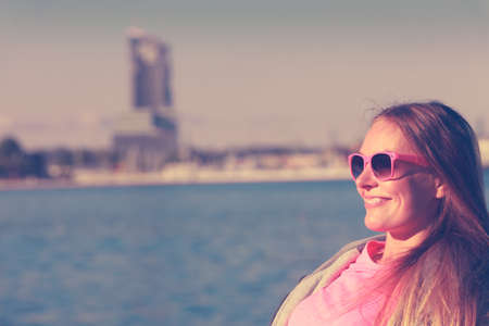 Sport, workout fashion concept. Woman wearing sunglasses and tracksuit resting, relaxing after doing sports outdoors near seaの写真素材
