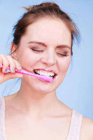 Woman brushing cleaning teeth. Girl with toothbrush. Oral hygiene. Blue backgroundの写真素材