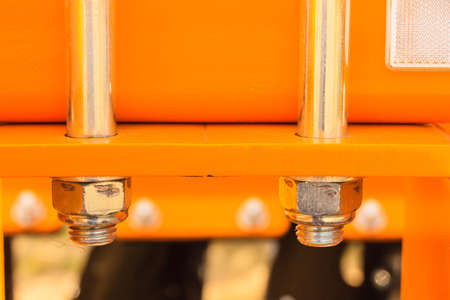 Construction machines concept. Detailed closeup of screws and bolts on yellow indrustrial machinery