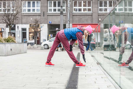 Sport and recreation. Fit slim sporty teen girl stretching warming up outdoor on city street. Woman...