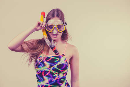 Woman wearing swimsuit with snorkeling mask having fun studio shot, Happy joyful girl dreaming about active summer vacation. Snorkeling swimming conceptの写真素材