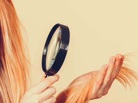 Haircare, health problem concept. Unhappy blonde woman looking at ends of her blonde hair through...