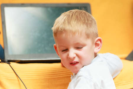 Children and technology, spending free time online concept. Little boy using laptop computer playing...