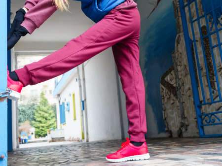 Sport and recreation. Fit slim sporty teen girl stretching warming up outdoor on city street. Woman exercising on fresh air.の写真素材