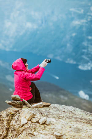 Tourism vacation and travel. Female tourist taking photo with camera, enjoying mountains landscape from Dalsnibba viewpoint, Norway Scandinavia.の写真素材