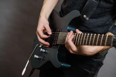 Male hands with electric guitar. Close up, part body adult person is holding instrument and playing. Hobby, music conceptの写真素材