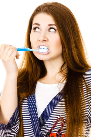 Woman wearing dressing gown brushing cleaning teeth. Funny girl with toothbrush. Oral hygiene. Isolated on whiteの写真素材