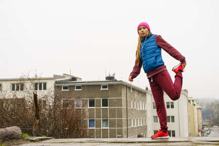 Sport and recreation. Fit slim sporty teen girl stretching warming up outdoor on city street. Woman...