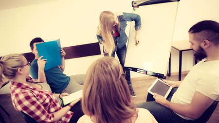 Teaching Concept. Female speaker in front of whiteboard screen giving presentation, participants...
