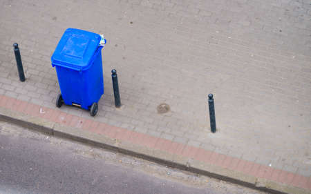Cleanliness in city objects concept. Minimalist photo of blue trash can on street pavementの写真素材