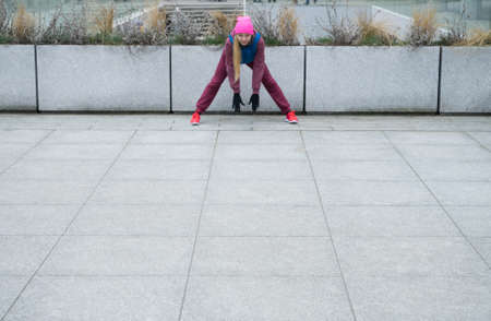 Sport and recreation. Fit slim sporty teen girl stretching warming up outdoor on city street. Woman...