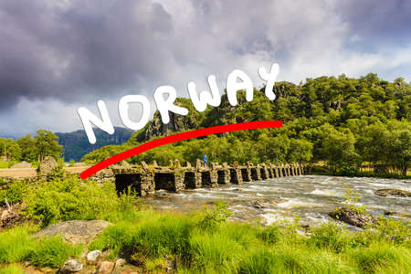 Tourist woman standing on stone slab bridge Terland Klopp in Norway Dalane region.