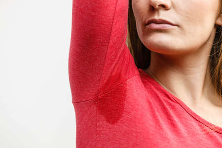 Sweaty girl pointing at wet stain under arm. Bad sweating problem.