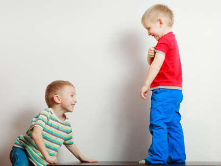 Childhood, relationship between brothers concept. Two little boys siblings playing together on table having fun.の写真素材