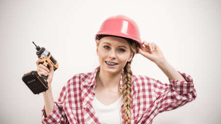 Young woman using driil power tool for her work at home. Girl working at flat remodeling. Building,...