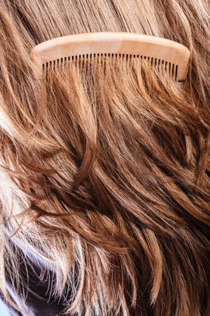 Haircare concept. Straight brown hair with wooden comb closeupの写真素材