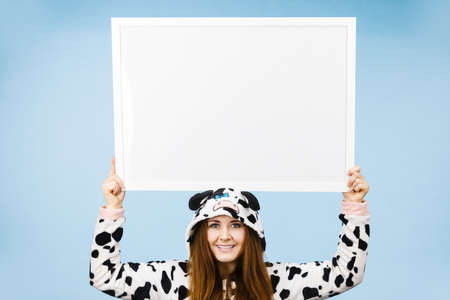 Smiling teenage girl in funny nightclothes, pajamas cartoon style with blank empty banner board. Advertisement copyspace.の写真素材