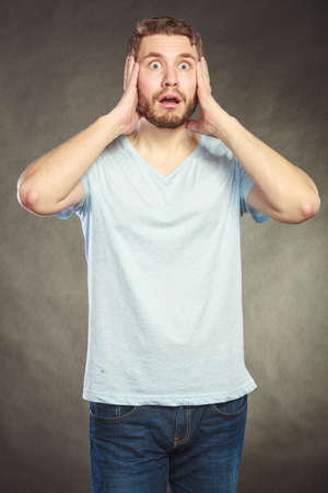 Portrait of scared afraid shocked handsome man in shirt. Young guy posing in studio on black.の写真素材