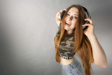 Cheerful teenage woman listening to music through big headphones having fun. Bizarre crazy close up.の写真素材