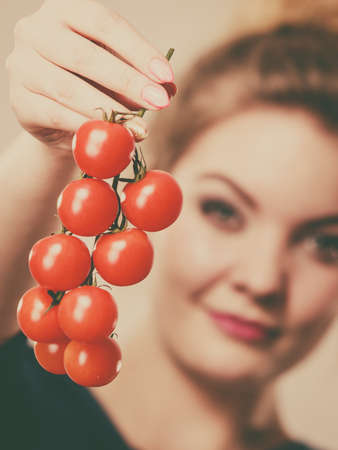Organic vegetables and food concept. Happy positive smiling woman holding fresh cherry tomatoesの写真素材