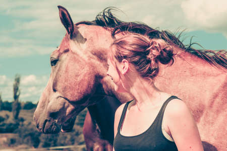 Animal and human love, equine concept. Jockey woman taking care of horse