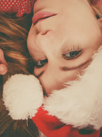 Happy woman waiting for Christmas season wearing pajamas and Santa Claus hat lying in bed.の写真素材
