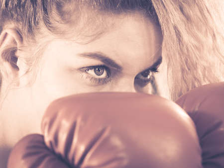 Sporty angry determined woman wearing red boxing gloves, fighting. Studio shot on dark background.の写真素材