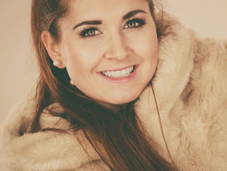 Happy attractive woman wearing light furry warm cozy coat with hood perfect for winter. Cold days fashion concept.の写真素材