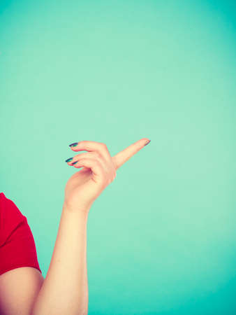 Advertising things concept. Woman hand pointing at empty copyspace. Studio shot on blue backgroundの写真素材