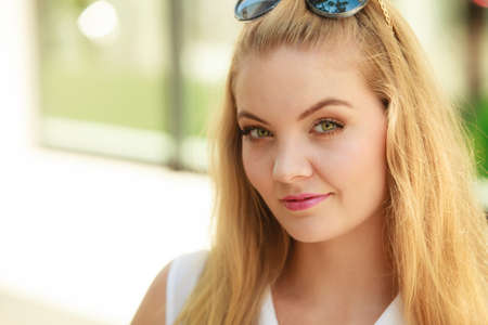 Portrait of beautiful, attractive blonde woman with sunglasses on her head. Outdoor shot on sunny dayの写真素材