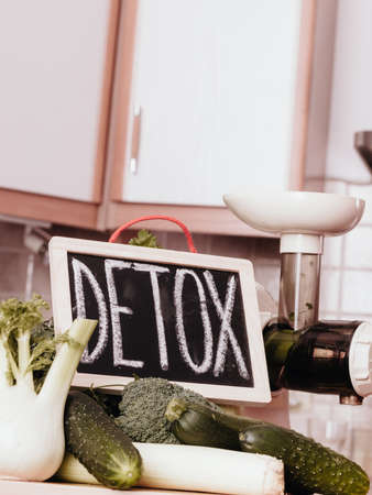 Many green vegetables in kitchen standing next to board with detox sign.の写真素材