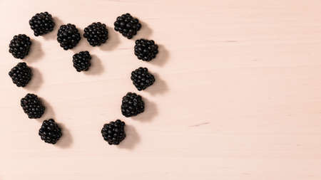 Fresh berries of blackberry fruits blackberries in form shape heart on wooden table background. Concept for healthy eating and nutrition. Top viewの写真素材