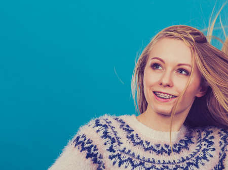 Hairstyles ideas, happiness concept. Crazy teenage woman wearing winter jumper with windblown blonde hairの写真素材