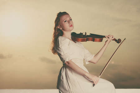 Music love, hobby and everyday passion concept. Woman on beach near sea playing on violinの写真素材