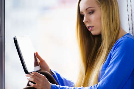 Modern technology education internet, digital online learning concept. Long hair teen girl with tablet pc computer on window sillの写真素材