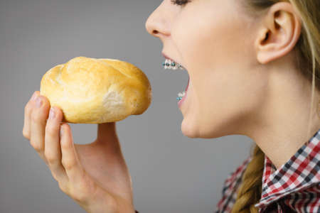 Woman holding bun bread roll enjoying her healthy morning breakfast. Wheat food.
