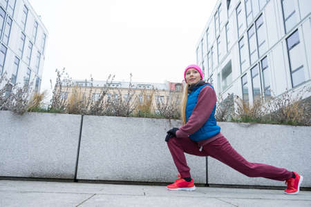 Sport and recreation. Fit slim sporty teen girl stretching warming up outdoor on city street. Woman...