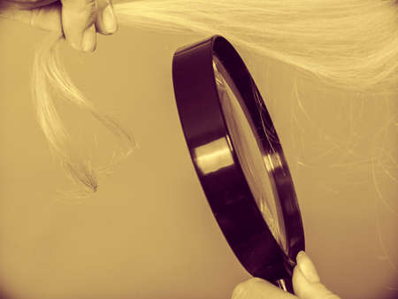 Haircare, health problem concept. Unhappy woman looking at ends of her blonde hair through...